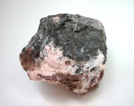Das seltene Tonmineral Sudoit als derbe blassrosa Massen neben Pyrolusit. 5 cm breites Stück..jpg